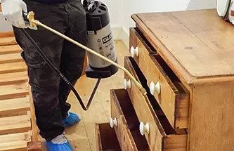 Pest expert spraying a cupboard against woodworms